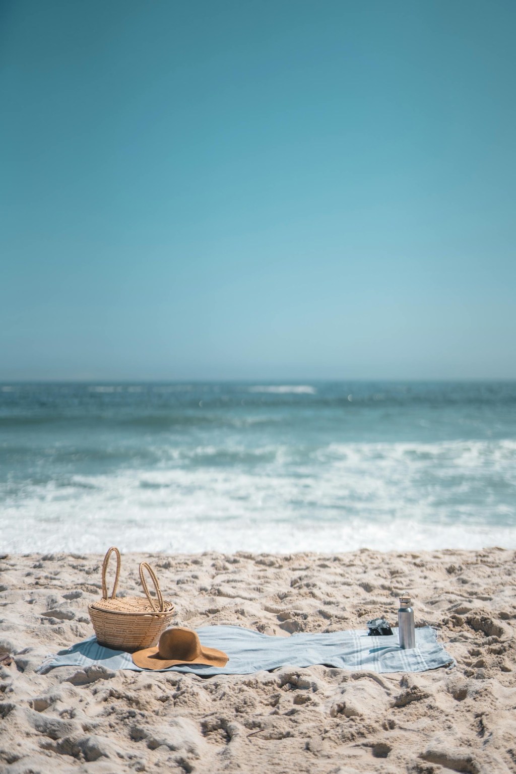 bag and summer hat on towel on a beach during a summer day