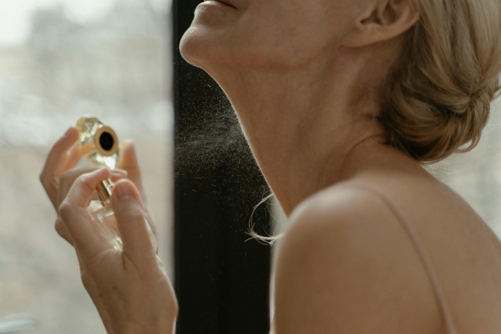 woman spraying perfume on neck