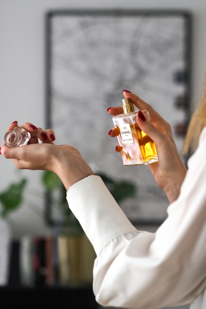 Elegant woman applying luxury perfume indoor